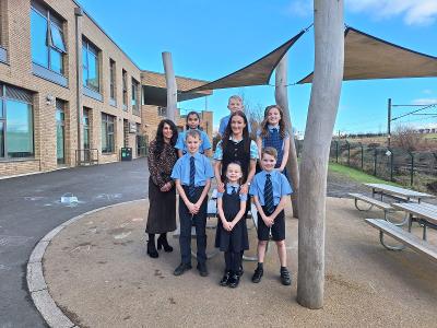 St Thomas' Primary pupils standing in the playground with 2 members of staff